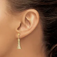 A person wearing a gold lighthouse-shaped dangle earring with a textured spiral pattern on the tower, shown from the side view of their ear.