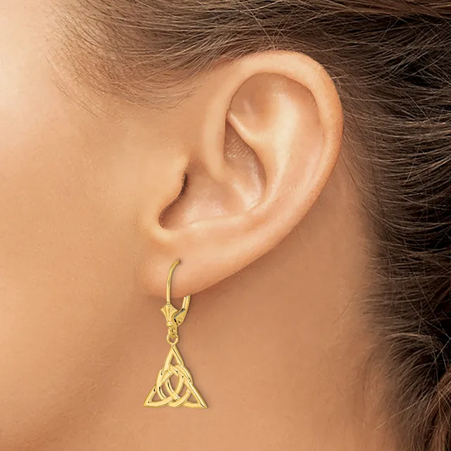 A gold-toned triangular pendant earring with interlocking Celtic knot design hangs from a lever-back hook on a model's earlobe.