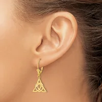 A gold-toned triangular pendant earring with interlocking Celtic knot design hangs from a lever-back hook on a model's earlobe.