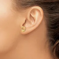 A person wearing a small gold stud earring shaped like a lobster or crab clasp in their earlobe.