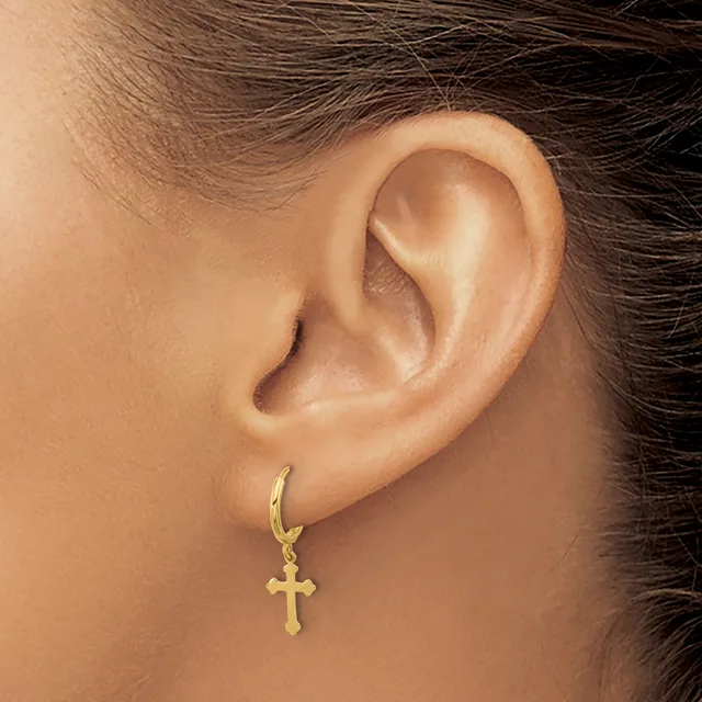 Close-up of a person's ear wearing a gold hoop earring with a small cross pendant attached.