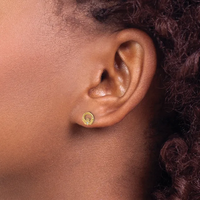 A person wearing a small gold circular earring with a textured or hammered finish in their earlobe, shown in profile view.