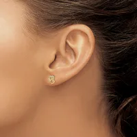 A person wearing a small gold stud earring with diamond accents on their earlobe, shown in profile view.