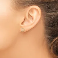 A person wearing a small curved crescent-shaped earring with diamond accents in the earlobe, shown from the side profile.