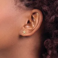 A small gold star-shaped stud earring in a pierced earlobe, shown in profile view against skin tone.