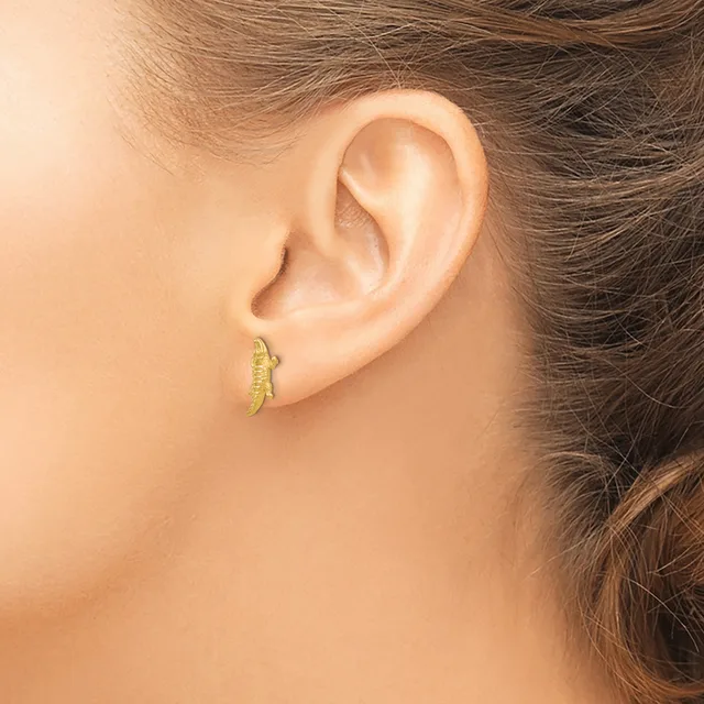 A person wearing small gold curved crescent-shaped earrings in their pierced earlobes, shown from the side view of their head and ear.
