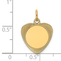 Gold-colored heart-shaped pendant with a polished circular center and textured radiating pattern on the outer edges, shown next to a ruler measuring approximately 0.75 inches tall.