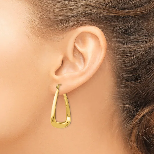 A woman wearing a gold-toned teardrop-shaped hoop earring in her earlobe, shown in profile view against her neck and shoulder.