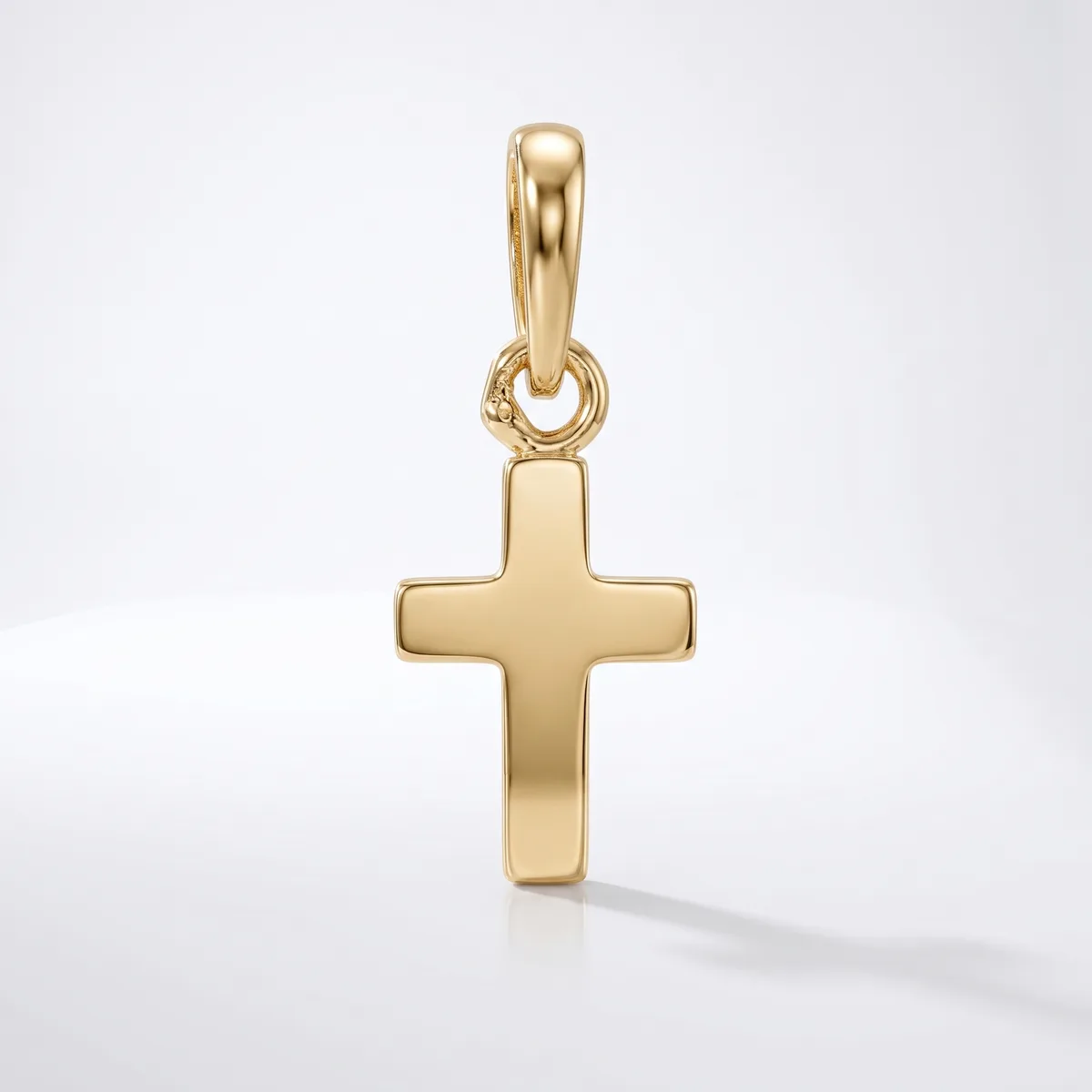 A gold cross pendant with a polished finish and rounded edges, suspended from a matching gold bail, displayed against a white background.