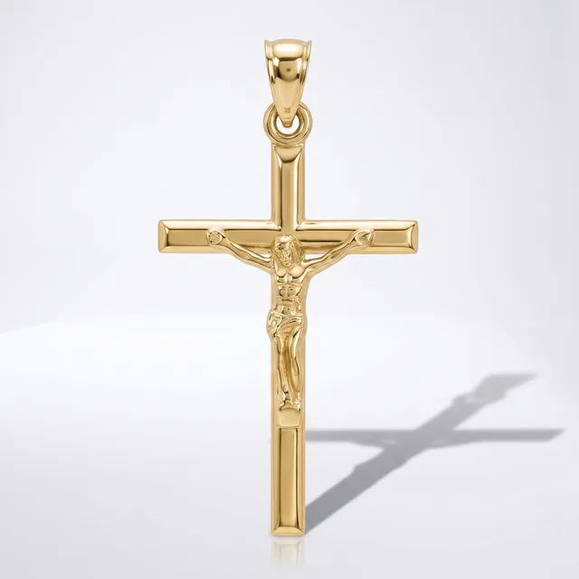 A gold crucifix pendant with a polished finish and detailed corpus figure, shown against a white background with its shadow visible.