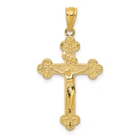 Gold crucifix pendant with ornate trefoil ends and a corpus figure, shown hanging from a bale against a white background.
