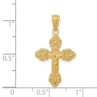 Gold ornate cross pendant with decorative scrollwork at the terminals, shown next to a ruler indicating approximately one inch in height.