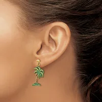 A woman wearing a gold-toned dangle earring shaped like a palm tree with green enamel detailing, shown from the side view of her ear.