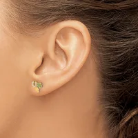 A person wearing a small jeweled stud earring with green and clear crystals in the earlobe, shown in profile view.
