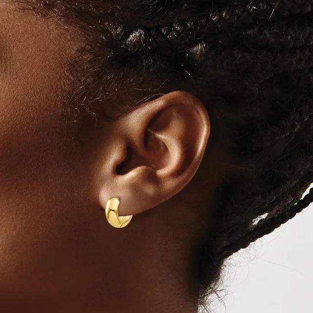 A person wearing a gold crescent-shaped hoop earring in their earlobe, shown in profile against a neutral background.