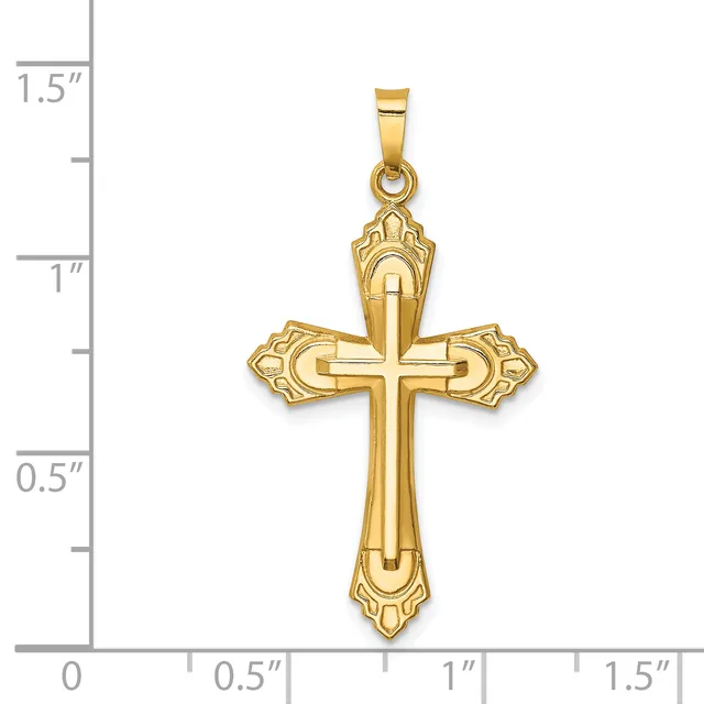 A gold cross pendant with ornate flared ends and a small stamped hallmark, shown next to a ruler measuring approximately 1.25 inches tall.