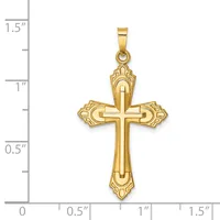 A gold cross pendant with ornate flared ends and a small stamped hallmark, shown next to a ruler measuring approximately 1.25 inches tall.
