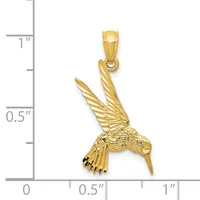 A gold hummingbird pendant with detailed wing and feather texturing, shown next to a ruler indicating its size is approximately one inch tall.