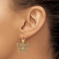 A person wearing a gold filigree butterfly earring on a fish hook wire, shown from the side view of their ear and face.