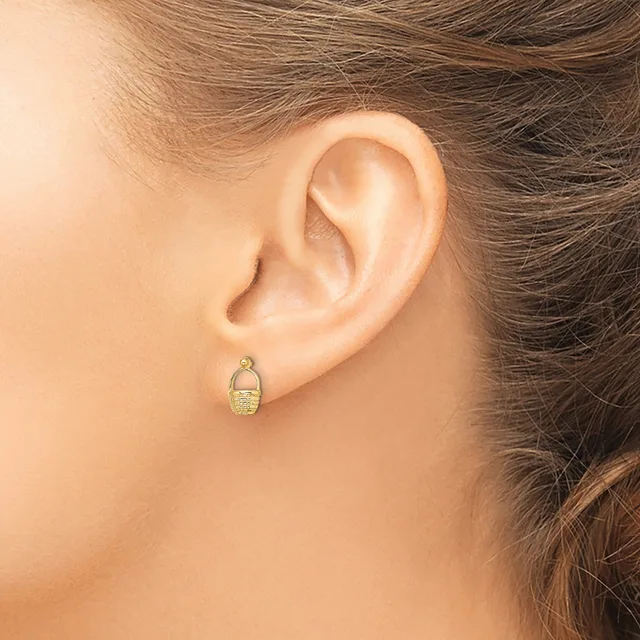 A person wearing a small gold oval earring with a textured surface, shown from the side profile view of their ear.