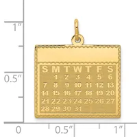 Gold rectangular pendant with a calendar design showing days of the week and numbered dates, displayed next to a measurement ruler.