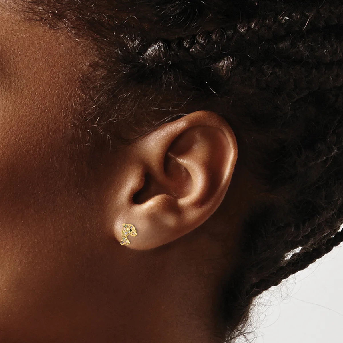 A person wearing a small gold teardrop-shaped earring with a textured finish and small gemstone accent, shown from the side view of their ear.