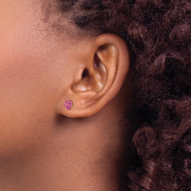 A close-up side view of a person's ear wearing a small purple heart-shaped stud earring.