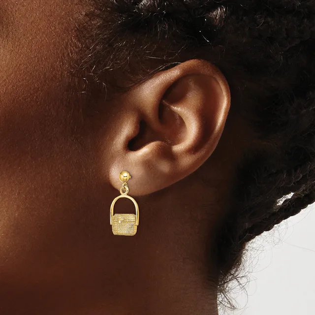 Gold-toned dangle earrings with small round studs and small rectangular basket-shaped pendants hanging from a person's ear.