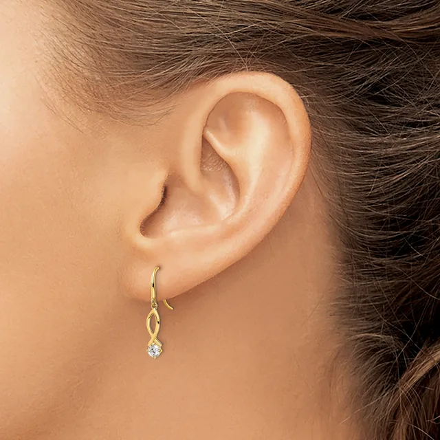 A person wearing a gold drop earring with a twisted wire design and a small round diamond or crystal stone, shown from the side view of their ear.