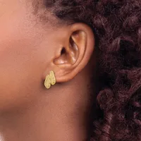 A person wearing textured gold hoop earrings with a crosshatch pattern, shown in profile with dark curly hair and brown skin.
