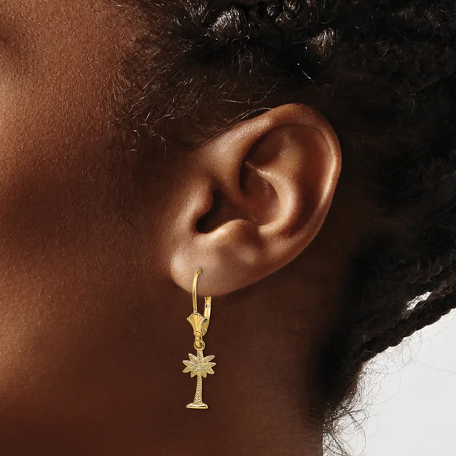 A person wearing gold drop earrings with cross-shaped pendants hanging from hook-style findings.