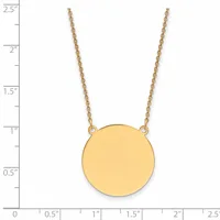 A gold circular pendant hangs from a delicate gold chain, displayed against a measurement scale showing the pendant is approximately one inch in diameter.