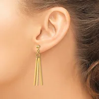 A person wearing gold-toned tassel drop earrings with a stud post, shown from the side view of their ear and neck.