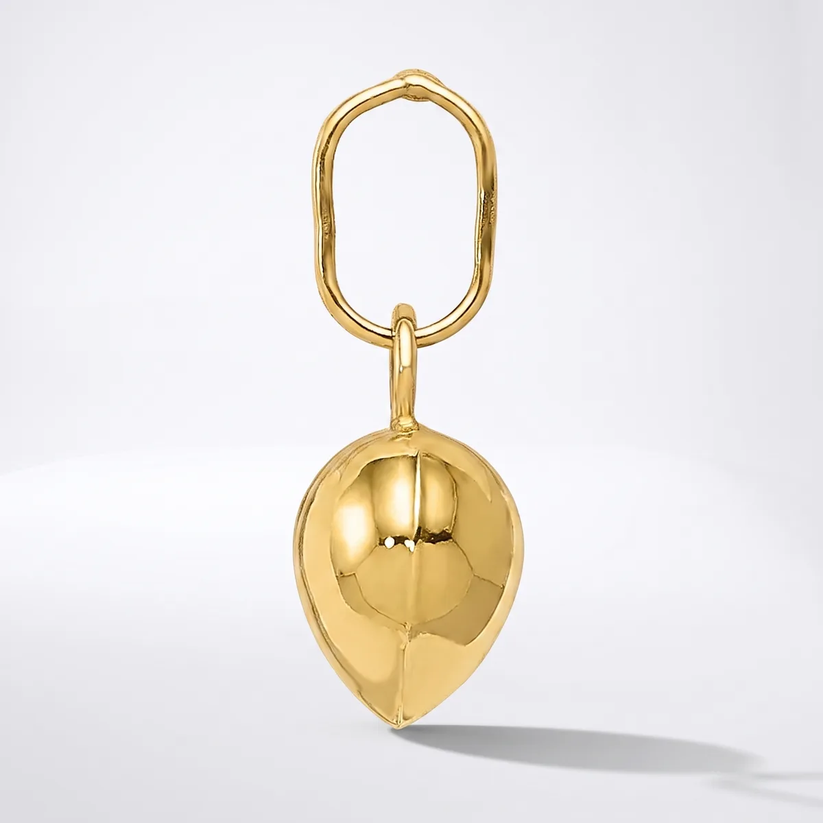 A polished gold-toned keychain featuring an oval loop at the top and a hollow spherical pendant with vertical seams hanging below it.