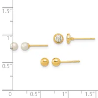 Three pairs of gold stud earrings displayed on a measurement scale: pearl studs, cubic zirconia studs, and polished ball studs.