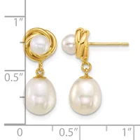 Pair of gold-toned drop earrings with twisted circular tops and dangling oval pearl drops, displayed against a measurement scale.
