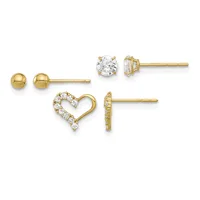 Four pairs of gold stud earrings displayed in a row: plain polished spheres, round clear gemstones in prong settings, heart outline with pave-set crystals, and a small geometric design.