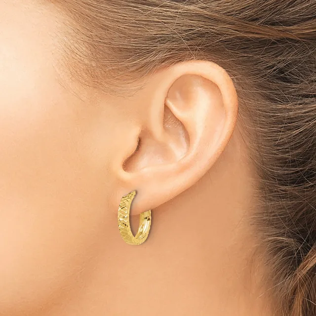 A person wearing textured gold hoop earrings with a hammered or dimpled surface finish, shown from the side view against their ear.