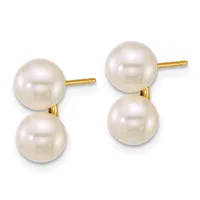 A pair of gold stud earrings, each featuring two lustrous cream-colored pearl spheres connected by a gold post and backing.