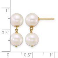 Pair of gold earrings with two white pearl drops suspended from studs, shown against a ruler measuring approximately one inch in length.