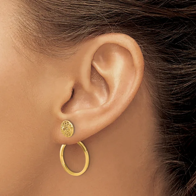A person wearing two gold earrings in one earlobe: a small textured stud and a larger polished hoop.
