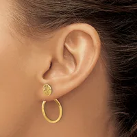 A person wearing two gold earrings in one earlobe: a small textured stud and a larger polished hoop.