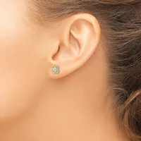 A person wearing a small oval stud earring with a cluster of light blue and clear stones set in metal, shown on their earlobe from the side.