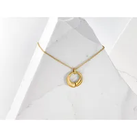 Gold-toned circular pendant necklace with a hollow center design, displayed on white marble surfaces.