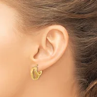 A person wearing small gold hoop earrings, shown from the side with brown hair pulled back, displaying the earrings at ear level.