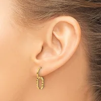 A close-up side view of a person's ear wearing a small gold textured oval hoop earring.