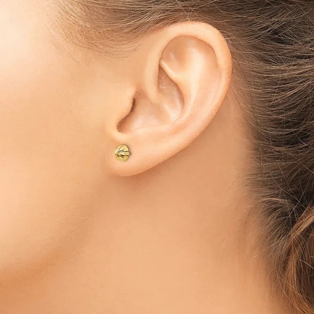 A small round gold stud earring with horizontal grooves worn on the earlobe of a person shown in profile.