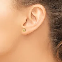 A small round gold stud earring with horizontal grooves worn on the earlobe of a person shown in profile.