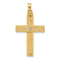 Gold cross pendant with vertical ribbed design, decorative curved elements on the horizontal bar, and a small diamond or crystal stone at the center intersection.
