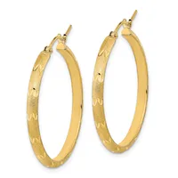 A pair of gold hoop earrings with textured surfaces and polished inner edges, displayed against a white background.